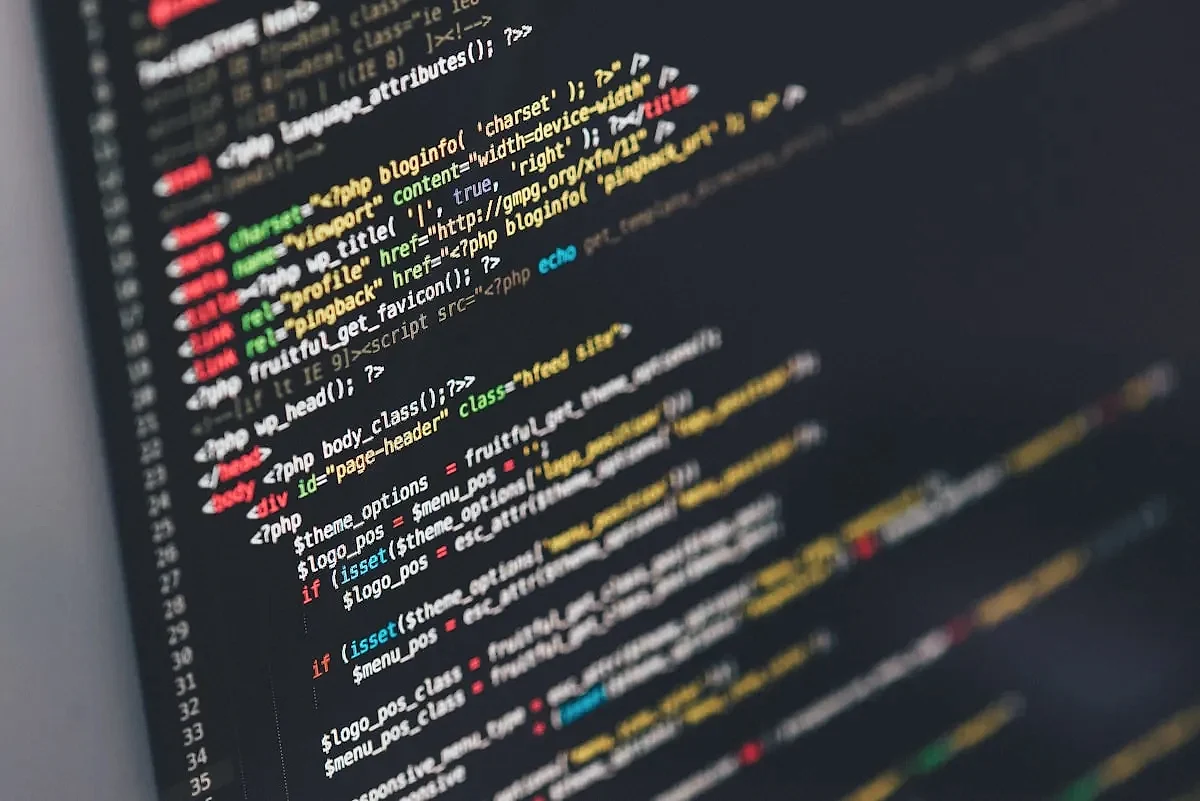 Web developer writing code on dual monitors in a professional London studio environment
